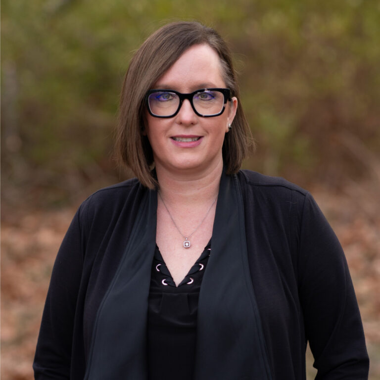 Beth Hylsky, team member at Duckett Ladd Advisors, posing outdoors in a black outfit, emphasizing expertise in financial services for dental practices.